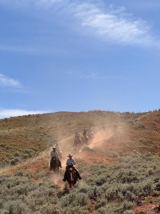 Riders galloping across stunning Wyoming wilderness