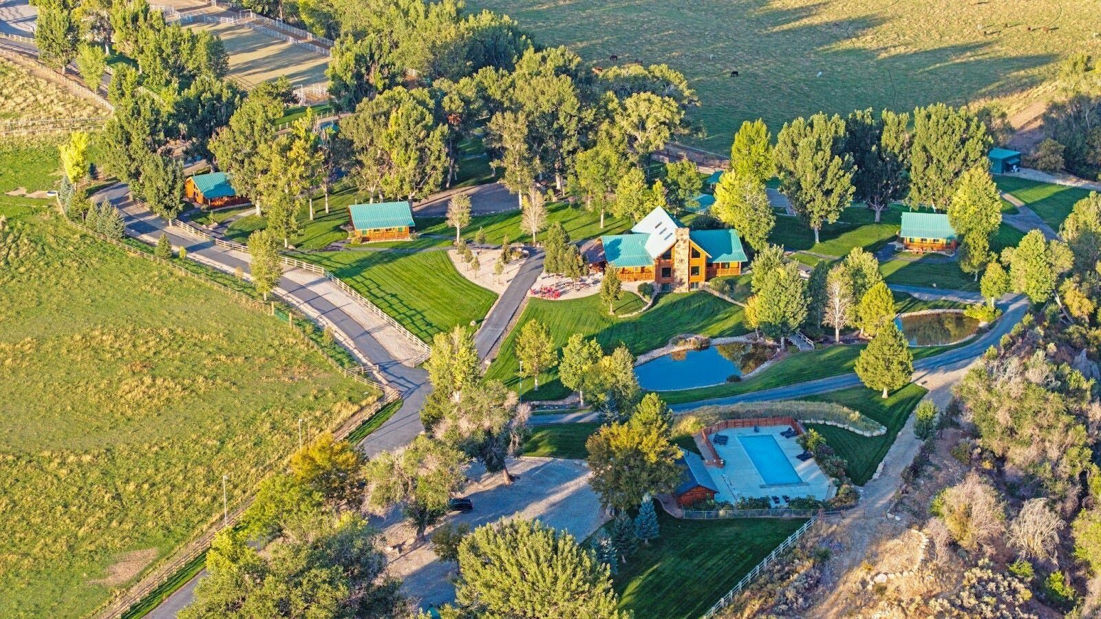 Aerial view of ranch buildings, tree-lined paths, and surrounding fields.