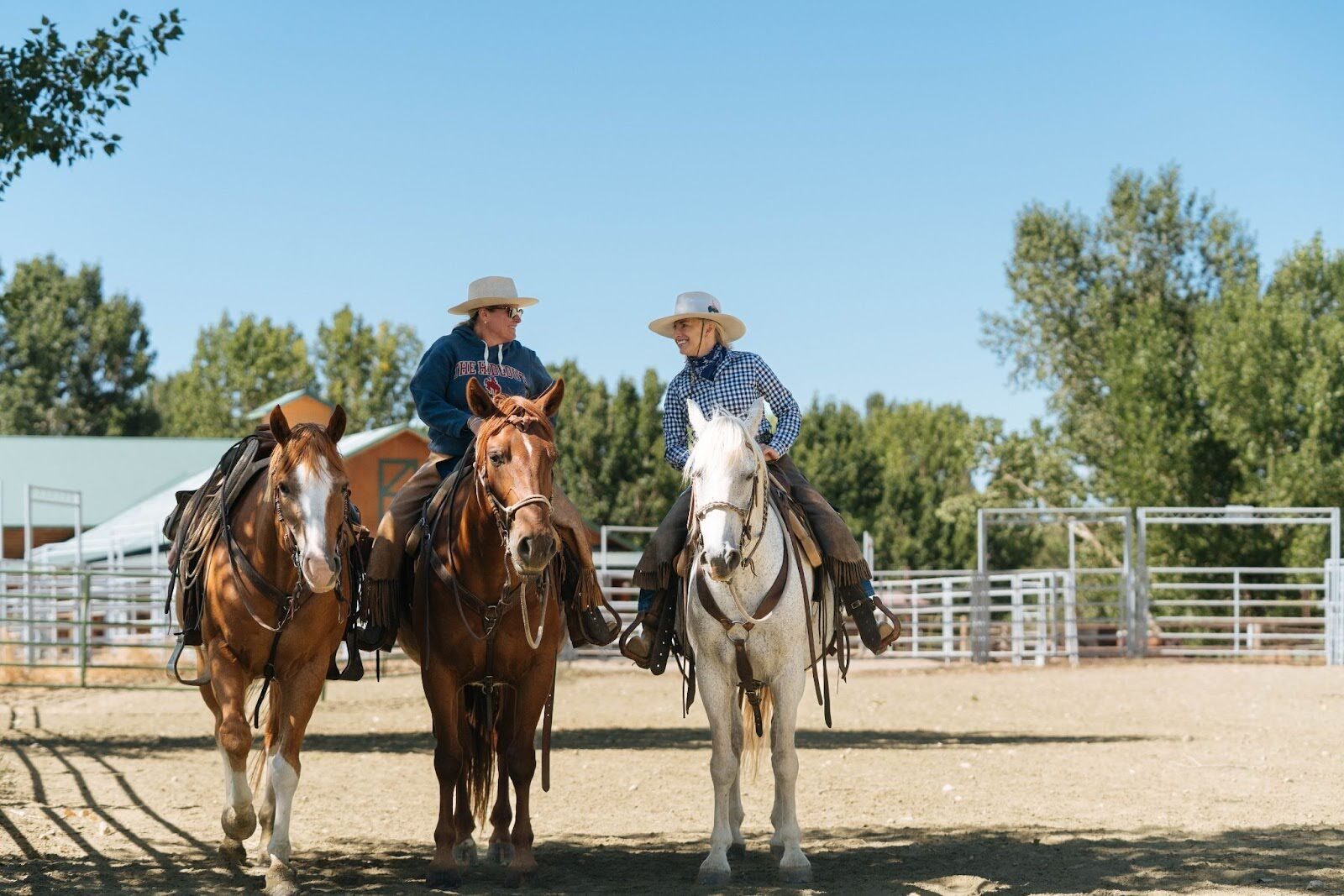 Three horseback riders together in a fenced riding area.