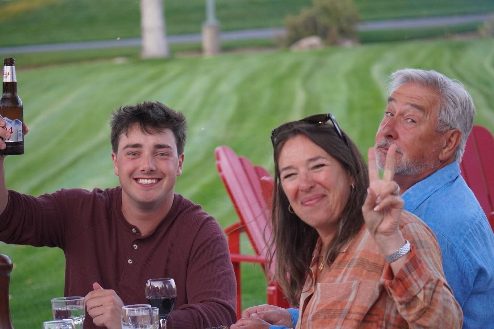 Three people relaxing in outdoor chairs on a lawn.