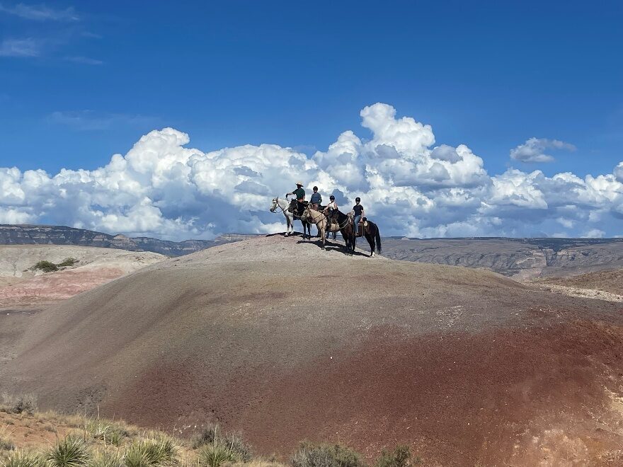Horseback riders crossing a red-rock landscape