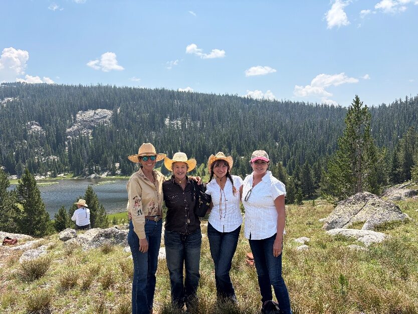 Four people standing together in a forested mountain clearing.