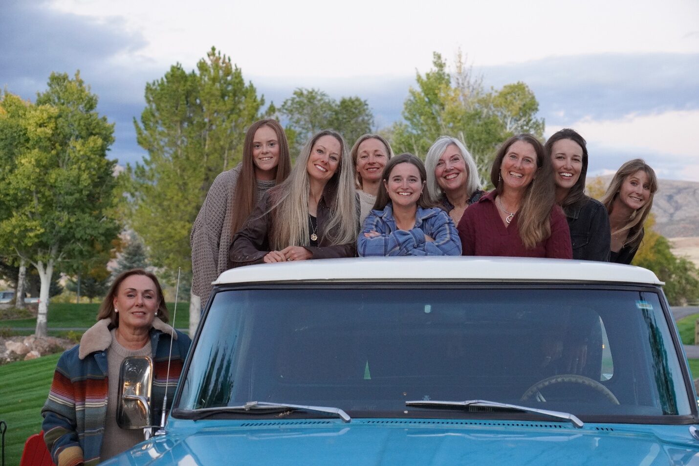 A group posing together around a blue pickup truck.